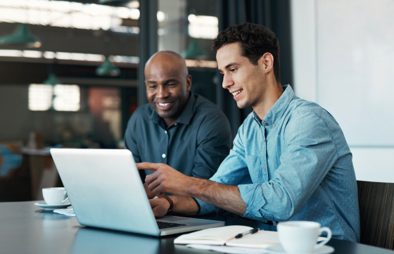 two guys looking at laptop on desk